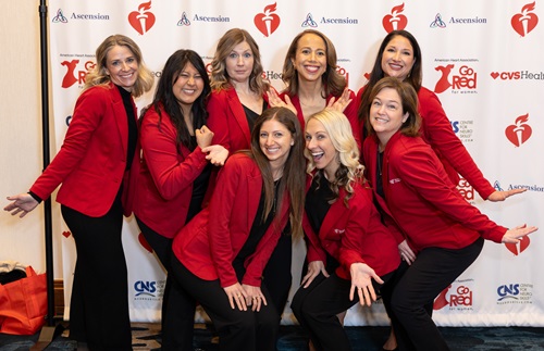 Group of eight women in red smiling in front of the American Heart Association Go Red for Women banner. Group of eight women in red smiling in front of the American Heart Association Go Red for Women banner.
