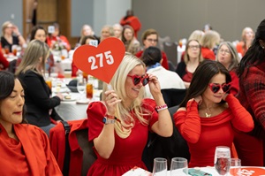 Photo of a woman in red heart shaped sunglasses holding up paddle number 275